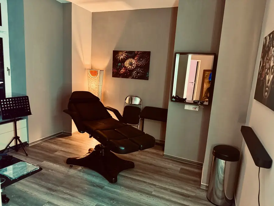 Arbeitsplatz mit schwarzer Tattoo-Liege und Stehlampe
