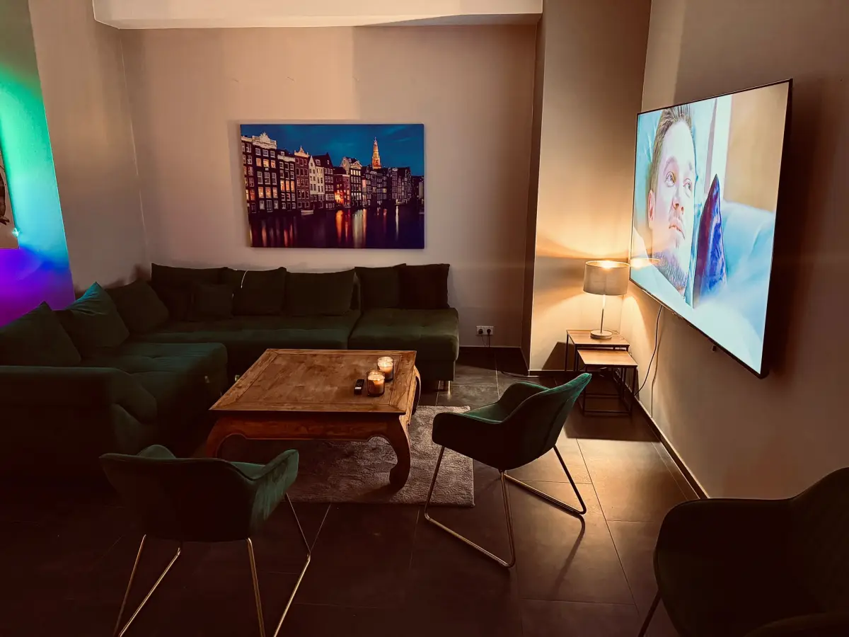 Lounge mit grünem Samtsofa, Kerzen und Wandbild