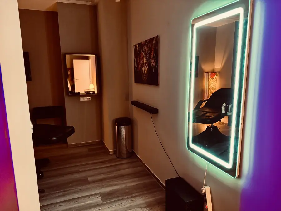 Neon-Spiegel, darin die Tattoo-Liege